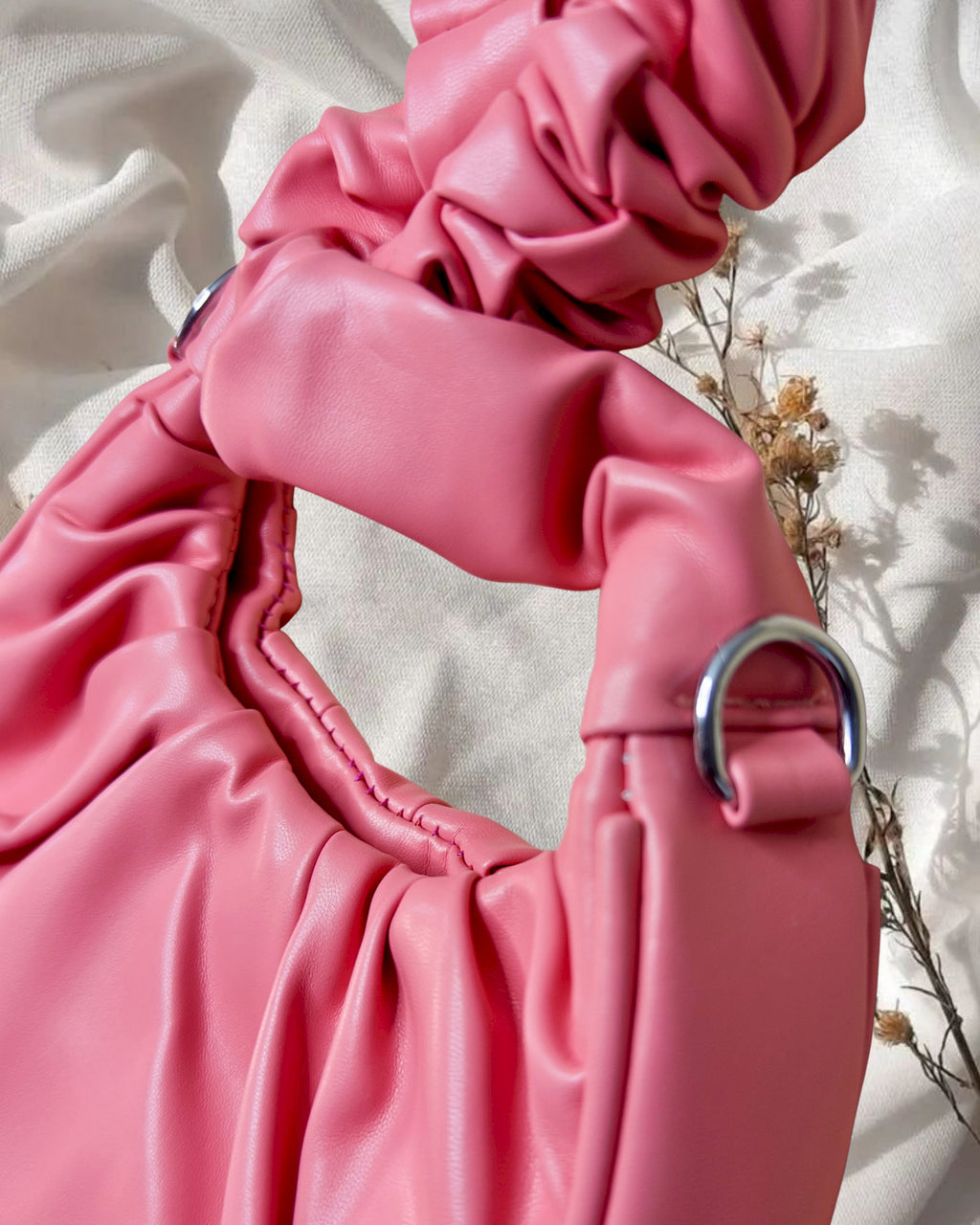 Close-up of a pink leather handbag with a metal ring on a light background