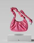 Pink handbag with a strap on a light gray background