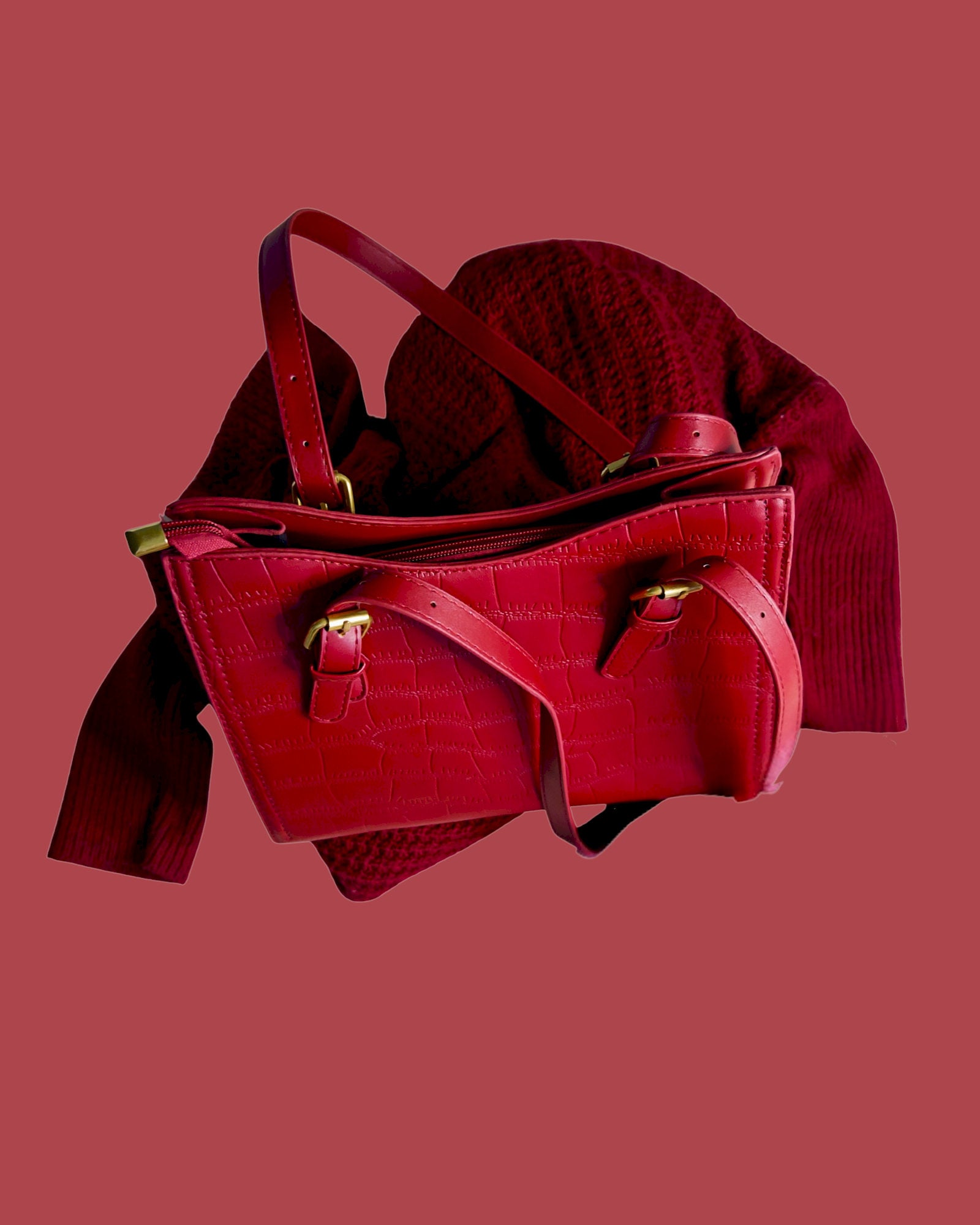 Red leather handbag with gold accents on a matching red background