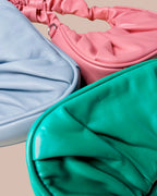 Three colorful headbands in pink, blue, and green on a beige background